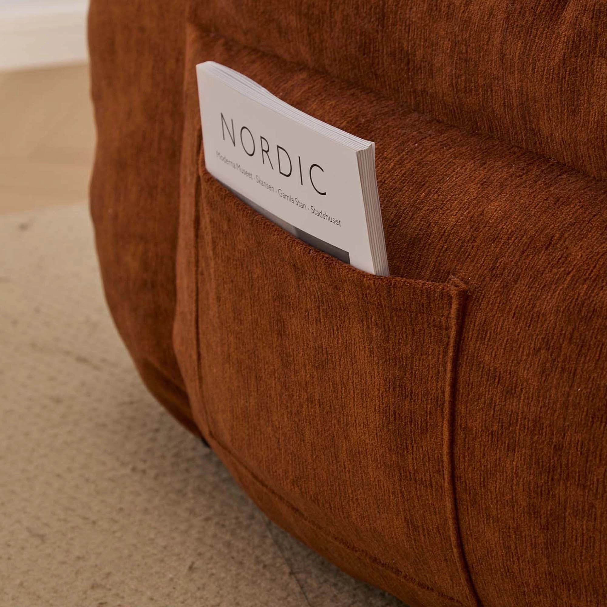 Sitzpolster mit NORDIC-Label am rostbraunen Rahmen eines kompakten Sessels