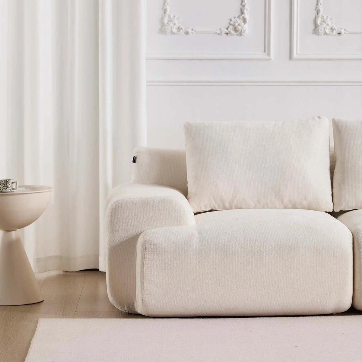 Komprimiertes Sofa in Weiß mit breiter Sitzfläche, Armlehnen und zwei großen Zierkissen